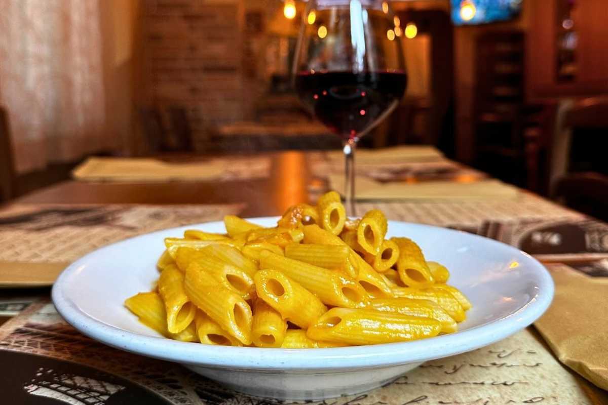 Piatto di pennette alla zucca con calice di vino rosso